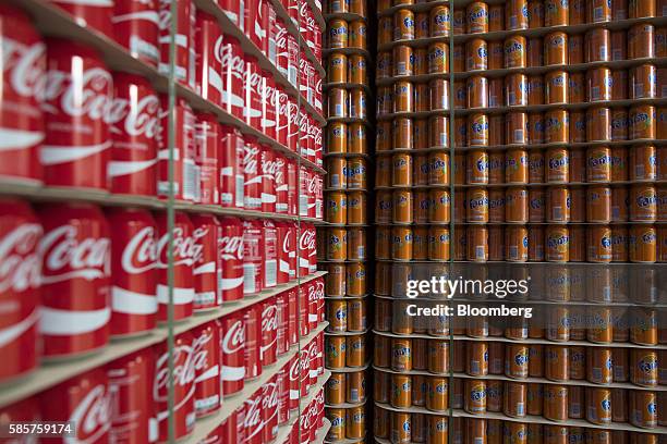 Cans of Coke and orange Fanta soft drink sit stacked on pallets in a storage area following manufacture at the Coca-Cola Co. Factory in Dongen,...