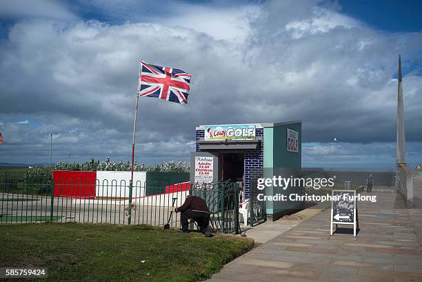 Man tends to the verges of a crzy golf course on the promenade of Rhyl seaside resort on August 3, 2016 in Rhyl, Wales. British seaside resorts are...