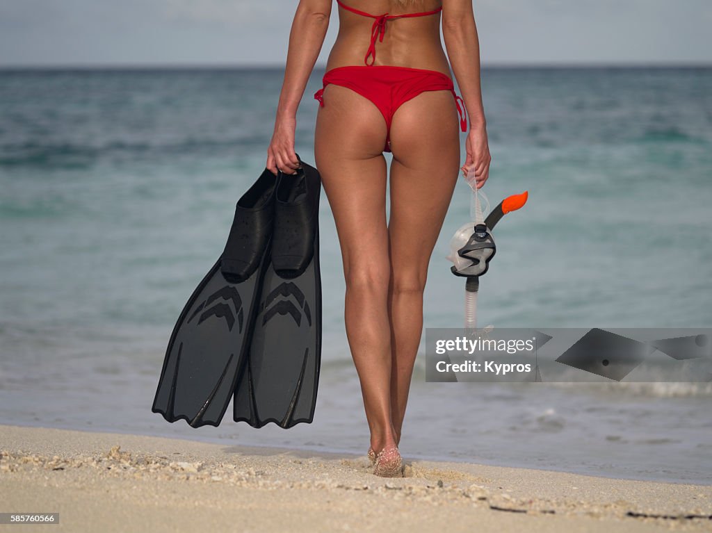 Asia, Maldives, Young Caucasian Woman Carrying Flippers, Dive Mask And Snorkel On Tropical Beach