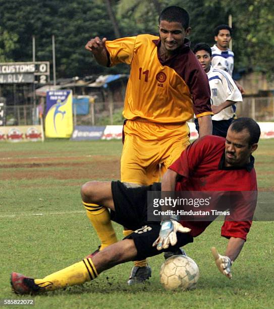 MUMBAI, INDIA OCTOBER 15, 2005: P.V. VINOY OF W. RAILWAY TRYING TO PUT THE BALL IN THE POST AS GOALKEEPER OF M.CUSTOMS BHUPAL SINGH BHIST TRYING TO...