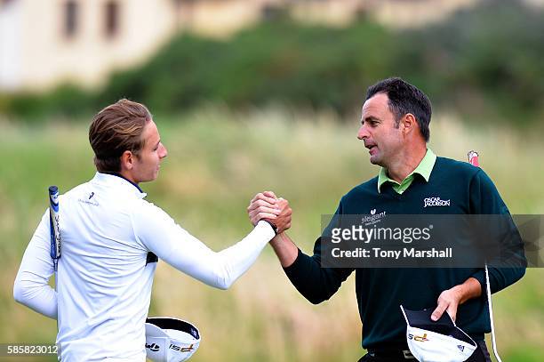 Richard Bland of England shakes hands with Joakim Lagergren of Sweden after winning the match on the green at hole 17 on day one of the Aberdeen...