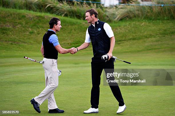 Chris Wood of England shakes hands with Brett Rumford of Australia after winning the match on hole 15 on day one of the Aberdeen Asset Management...