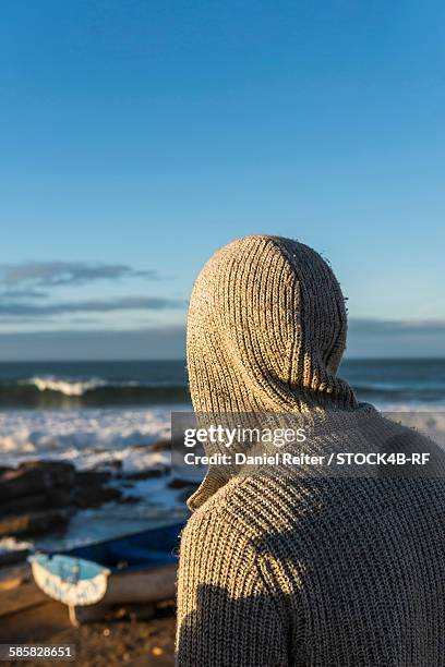 man with hooded jacket at the coast looking at the ocean, essaouira, morocco - travel african sunset rf photos only stock pictures, royalty-free photos & images