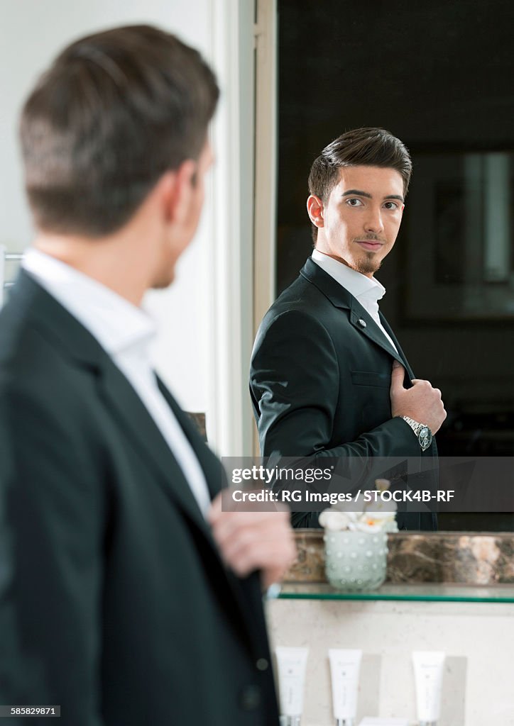 Elegant young man looking in mirror