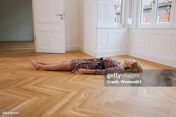 young woman lying alone on floor in an empty room - supino foto e immagini stock