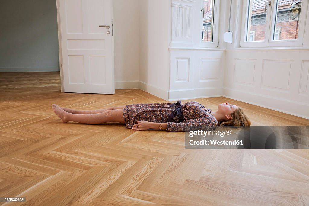 Young woman lying alone on floor in an empty room