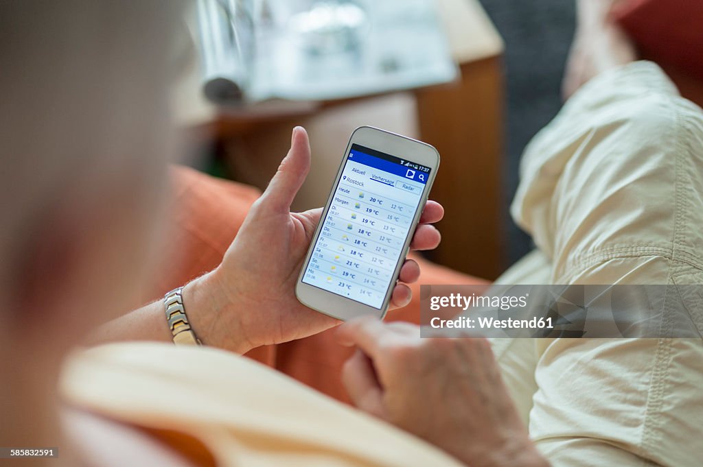 Senior woman looking at weather forecast on smartphone display