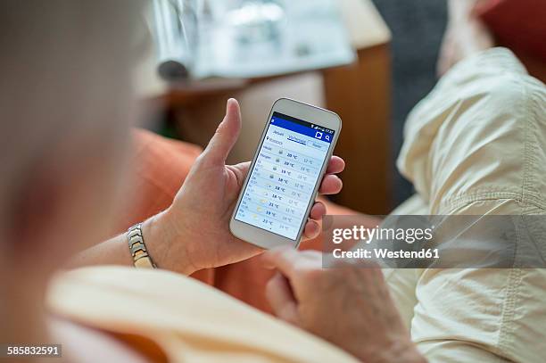 senior woman looking at weather forecast on smartphone display - meteorologie stockfoto's en -beelden