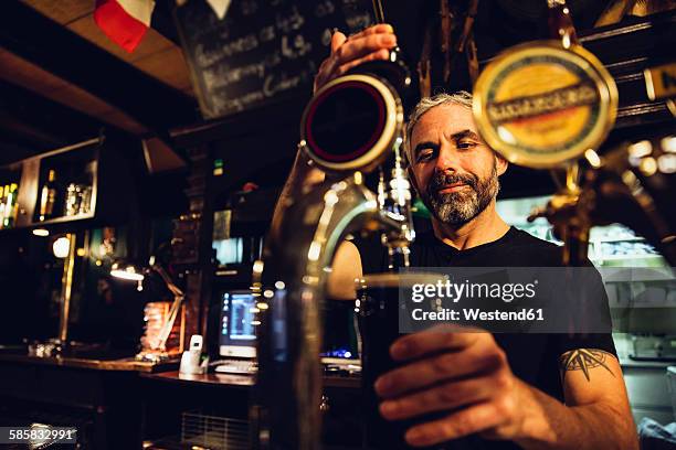 man tapping beer in an irish pub - barman fotografías e imágenes de stock