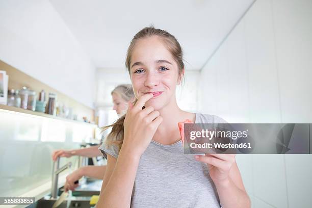 portrait of smiling teenage girl eating melon in the kitchen - finger in mouth fotografías e imágenes de stock