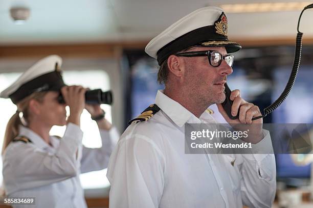 ship captain on bridge talking on radio - bootskapitän stock-fotos und bilder