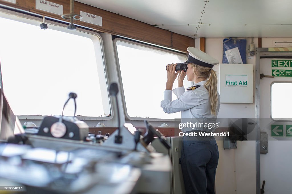 Deck officer on ship looking through binoculars