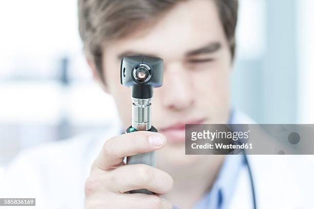 doctor looking through otoscope - otoscope fotografías e imágenes de stock