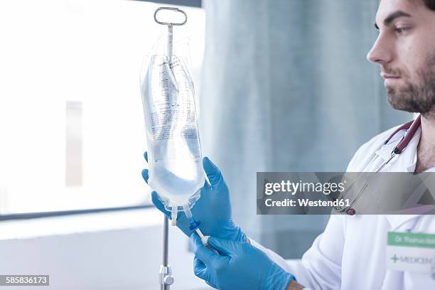 nurse adjusting intravenous drip - infuus met een fysiologische zoutoplossing stockfoto's en -beelden