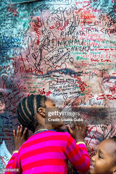 Vilakazi Street, Soweto, South Africa: South Africans react to the passing of Nelson Mandela; little girls hug a poster of the icon, outside his home...