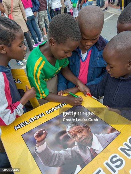 Vilakazi Street, Soweto, South Africa: South African children react to the passing of Nelson Mandela, signing their names and wishes on placards of...