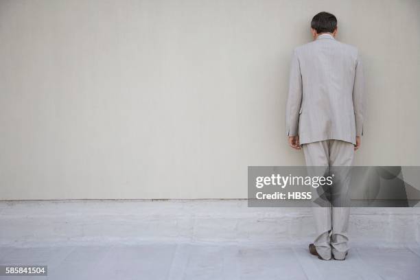 businessman standing and facing a wall - den kopf in den sand stecken stock-fotos und bilder