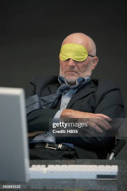 businessman wearing eye mask at his desk - computer wearing eye mask stock pictures, royalty-free photos & images