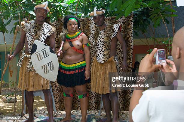 Member of the "Amasiko Esintu Upholdings" group photographs students with a cell phone, against a makeshift backdrop with hired Zulu traditional...