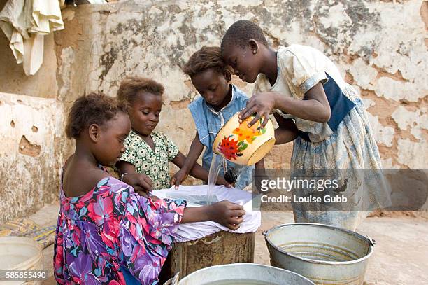 Rafia Fusseini and her sisters Fatima and Samata who suffered from multiple guinea worm wounds in 2007, filter their drinking water collected from...