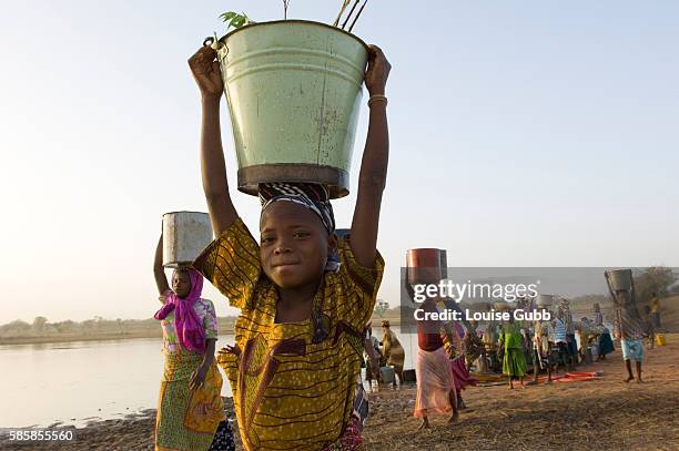 Young children carry their collection of daily water from the manmade dam, using foot-pedaled SOKA pumps or cloth filters to ensure their water is...