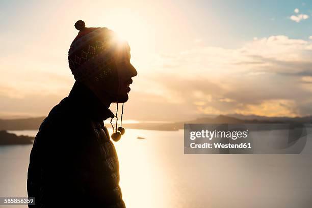 peru, silhouette of man with cap in front of lake titicaca at sunset - kontrastreich stock-fotos und bilder