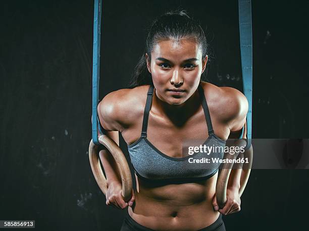 portrait of gym athlete with gymnastic rings - asian female bodybuilder stock-fotos und bilder