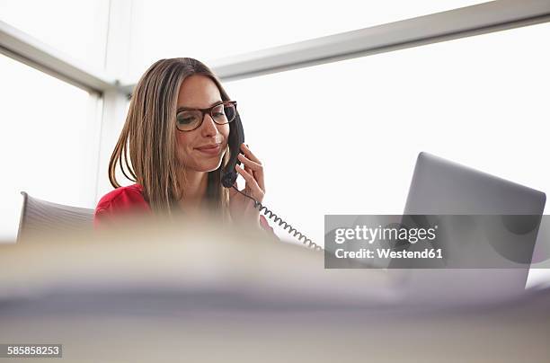 young woman in office on the phone - telefonhörer stock-fotos und bilder