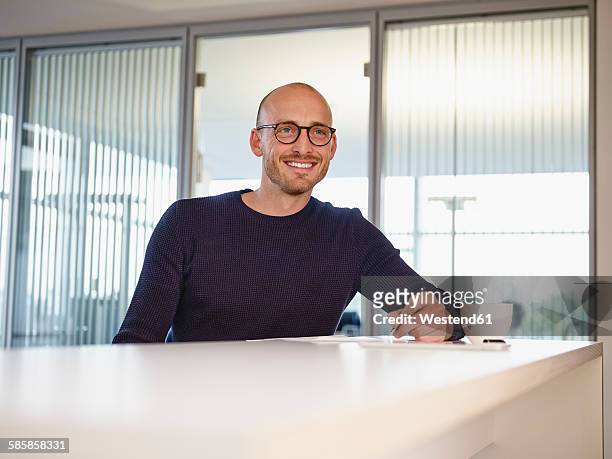 smiling man in office writing at counter - högt hårfäste bildbanksfoton och bilder