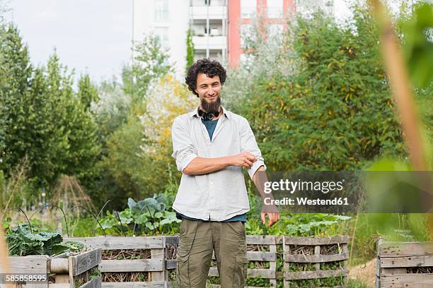 young man standing in an urban garden - rolling up sleeve stock-fotos und bilder
