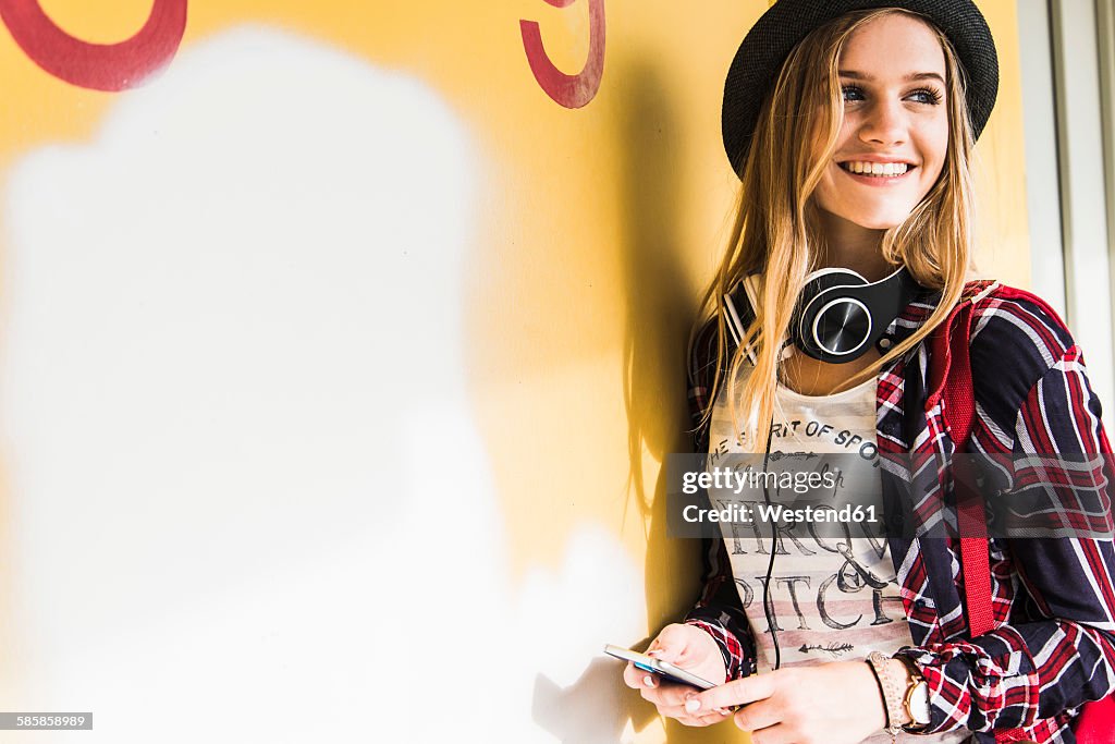 Smiling teenage girl leaning against wall