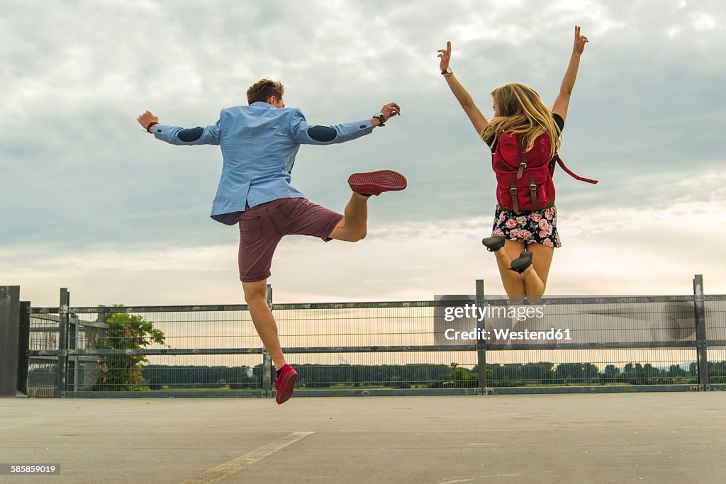 Enthusiastic young couple jumping on parking level