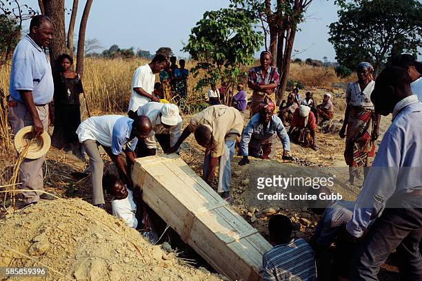 Mourners watch as a coffin is lowered into a grave, the deceased a victim of AIDS and mother of four young children, now orphans. Seventy percent of...