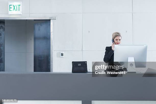 woman behind reception desk in hotel lobby on the phone - lobby screen stock pictures, royalty-free photos & images