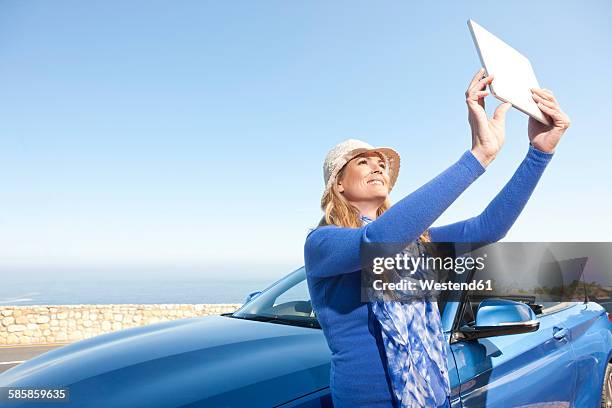 south africa, woman at a convertible taking pictures with a digital tablet - toyota south africa motors stock pictures, royalty-free photos & images
