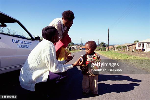 Hospice caregiver brings food and medications to a two year old boy, orphaned by AIDS and being raised by his aunt, in Gamalakhe, South Africa.
