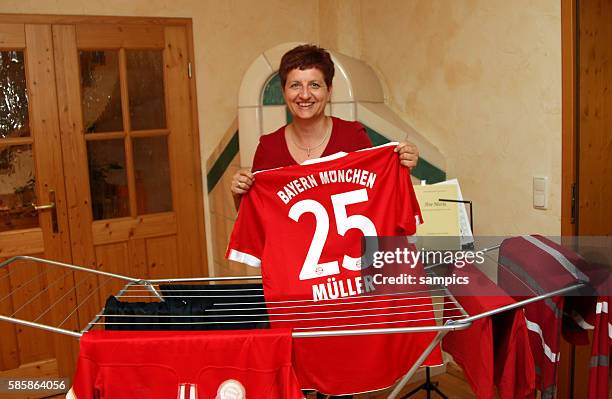 Mother of Thomas, Klaudia Mueller, holds up a Bayern Munich jersey of her son at home in Munich, Germany.