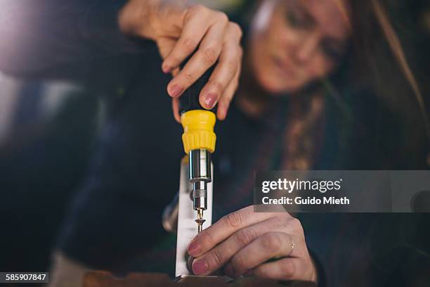 woman screwing a holder on a wood board - destornillador fotografías e imágenes de stock