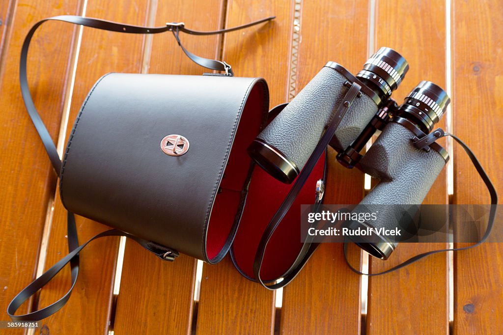 Binoculars with leather case on a wooden table