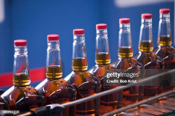 bottles of makers mark bourbon before wax sealing - kentucky bourbon stock pictures, royalty-free photos & images