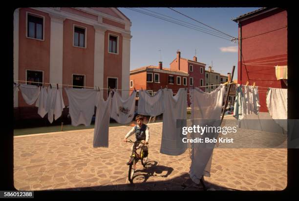 boy biking past laundry - italian boy stock pictures, royalty-free photos & images