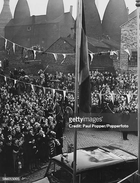Princess Elizabeth is greeted by cheering crowds as she arrives in the Royal car at the Paragon China factory, against the backdrop of Pot Banks or...
