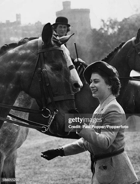 Princess Elizabeth strokes the horse 'Holyport' before presenting the third prize rosette to owner Mrs Selwyn Butcher at the Royal Windsor Horse...