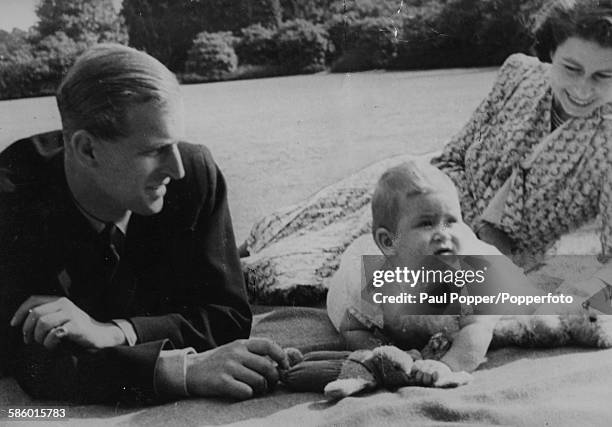 Princess Elizabeth and Prince Philip, the Duke of Edinburgh, playing with their young son Prince Charles in the gardens of the royal residence of...