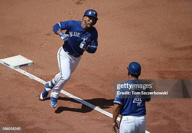 Devon Travis of the Toronto Blue Jays is congratulated by third base coach Luis Rivera after hitting a solo home run in the fifth inning during MLB...