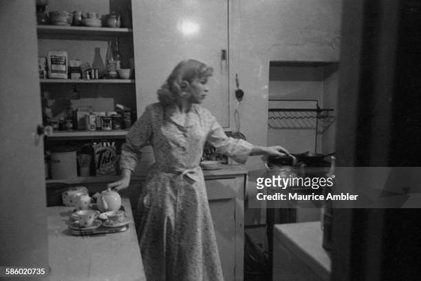Roberta Cowell , formerly Robert Cowell, making tea in a kitchen, March 1954. Roberta was once a Spitfire pilot, prisoner of war, racing motorist,...