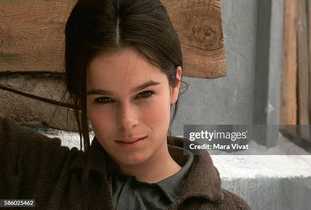 Actress Geraldine Chaplin stands against a wall.