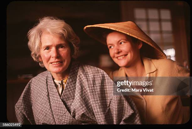 Photojournalist Margaret Bourke-White sits beside a friend wearing a Southeast Asian straw hat.