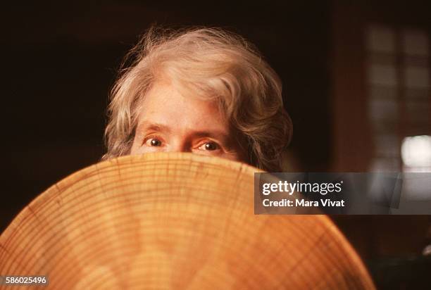 Photojournalist Margaret Bourke-White hides behind a Southeast Asian straw hat.
