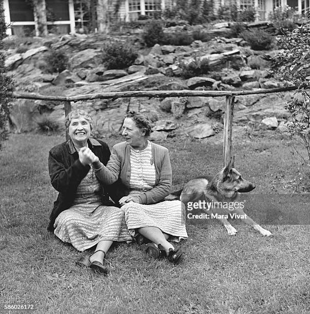 Teacher and author Helen Keller rests on a garden lawn with a friend and her guide dog. Keller achieved wide recognition by overcoming blindness and...
